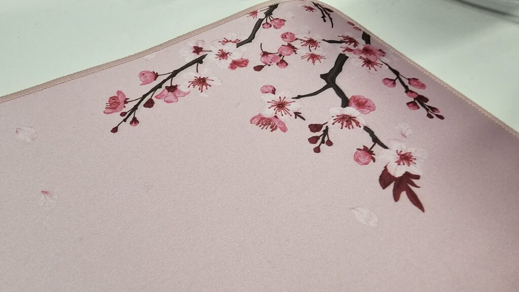 Close up of the pink cherry blossom mousemat. It's a soft pink colour with cherry blossoms in each corner. This is the top right corner.