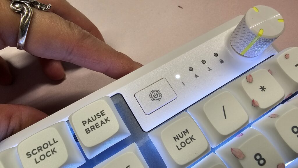 Close up of the Cherry Blossom keyboard showing the top right side of the keyboard with a dial and special iCUE button, it's sitting on a pink mousemat.