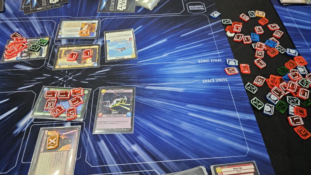 Star Wars Unlimited game area with several cards on the playing mat, and lots of counters, both on the cards and on the side ready to go.