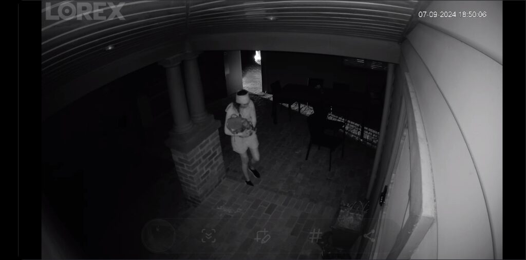 A black and white photo of a person walking up the stairs of the backyard.